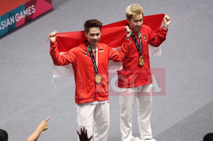 Marcus Fernaldi Gideon (kanan) dan Kevin Sanjaya Sukamuljo (kiri) membentangkan bendera Merah Putih usai menjuarai cabang bulu tangkis nomor ganda putra Asian Games 2018, Selasa (28/8/2018).