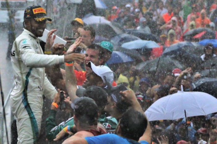 Pebalap Mercedes, Lewis Hamilton, menyapa penggemarnya setelah memenangi balapan GP Jerman di Sirkuit Hockenheim, Jerman, Minggu (22/7/2018).