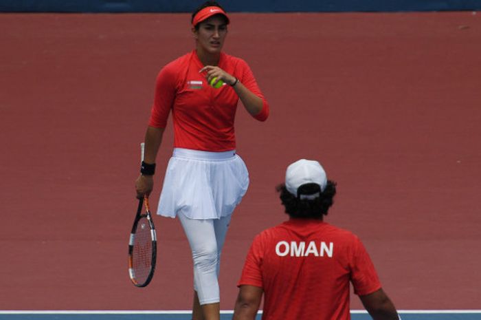 Petenis ganda campuran Oman Fatma Talib Sulaiman Al Nabhani (kiri) yang berpasangan dengan Muhammed Talib Sulaiman Al Nabhani bersiap melakukan servis pada pertandingan babak pertama tenis ganda campuran Asian Games ke-18 tahun 2018 di Venue Tenis Kompleks Jakabaring, Palembang, Sumatera Selatan, Minggu (19/8). 