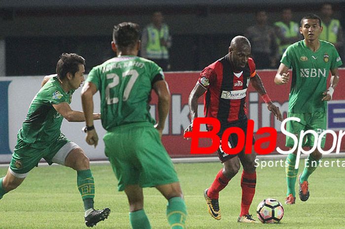 Penyerang Persipura Jayapura Boaz Solossa berusaha meloloskan diri dari tiga kawalan Bhayangkara FC 