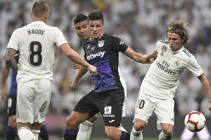 Aksi penyerang Leganes, Guido Carrillo (tengah), saat berduel dengan gelandang Real Madrid, Luka Modric (kanan), dalam pertandingan Liga Spanyol 2018-2019 di Stadion Santiago Bernabeu, Madrid, Spanyol, pada Sabtu (1/9/2018).