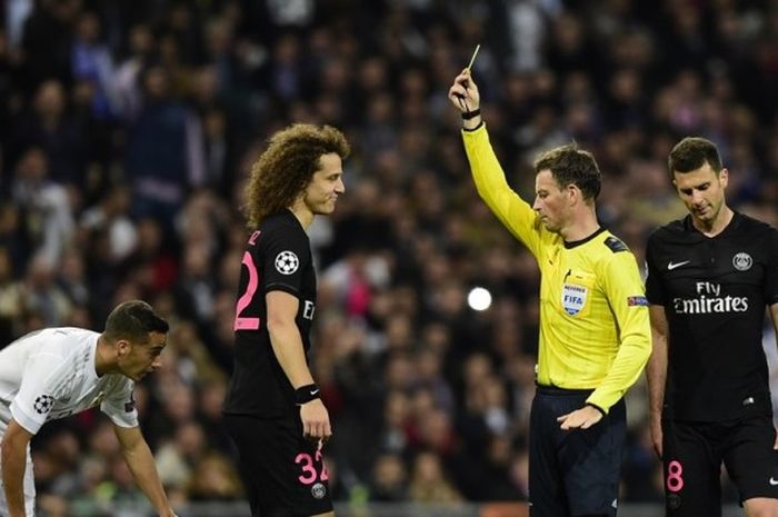 Wasit Mark Clattenburg (kuning) melayangkan kartu kuning kepada pemain belakang Paris Saint-Germain,