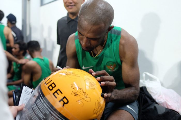 Pemain Timnas Indonesia Selection Boaz Salosa membubuhkan tanda tangan di helm Uber usai menjalani latihan di Lapangan ABC, Kompleks Gelora Bung Karno, Jumat (12/1/2018). 