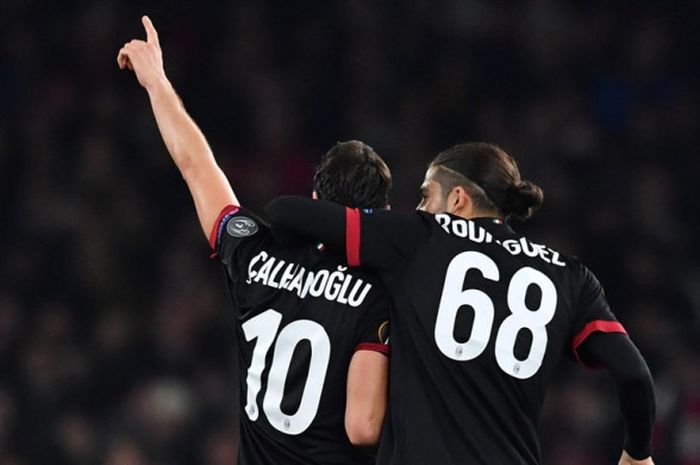 Gelandang AC Milan, Hakan Calhanoglu, merayakan golnya bersama Ricardo Rodriguez dalam laga leg kedua babak 16 besar Liga Europa kontra Arsenal di Stadion Emirates, London, Inggris, pada 15 Maret 2018.