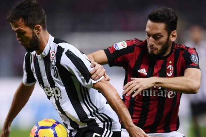 Gelandang Juventus, Miralem Pjanic, berusaha mempertahankan bola dari pemain AC Milan Hakan Calhanoglu pada laga yang berlangsung Sabtu (28/10/2017) di Stadion San Siro.