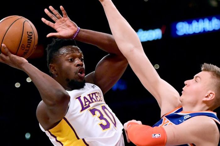 Pebasket Los Angeles Lakers, Julius Randle (jersey putih, #30), berupaya melepas passing saat dikawal pemain New York Knicks, Kristaps Porzingis (#6), pada laga lanjutan musim reguler NBA 2017-2018 di Staples Center, Los Angeles, California, Amerika Serikat, Minggu (21/1/2018). Lakers menang 127-107 atas Knicks.