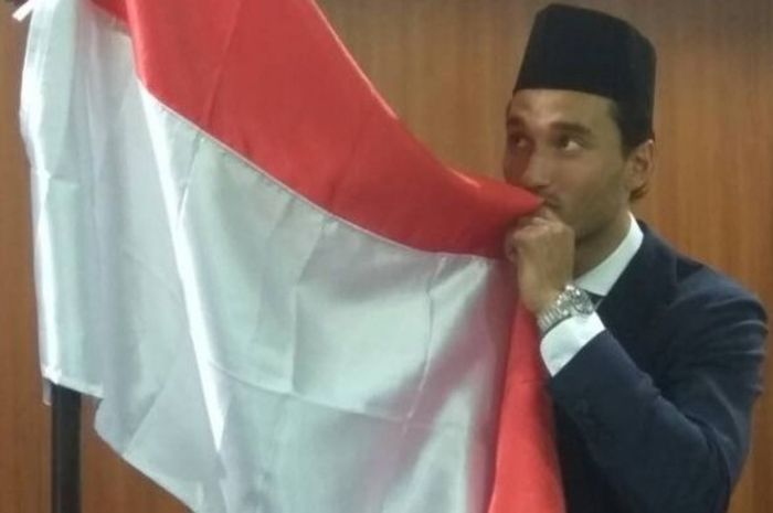    Pose pemain naturalisasi Indonesia, Ezra Walian, saat mencium bendera merah putih selepas disumpa