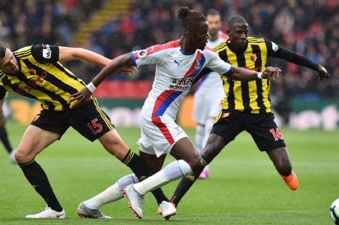 Pemain sayap lincah Crystal Palace, Wilfried Zaha, mencoba melewati hadangan pemain Watford, Craig Cathcart dan Abdoulaye Doucoure, dalam laga Liga Inggris pekan ketiga di Stadion Vicarage Road, London, Minggu (26/8/2018).