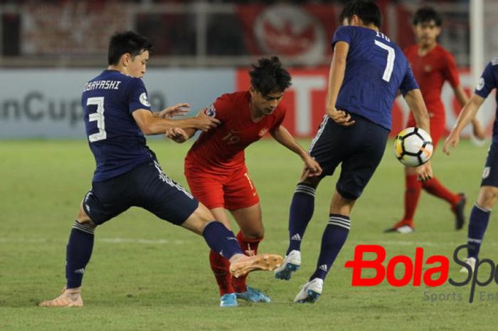 Penyerang timnas U-19 Indonesia, Hanis Saghara Putra diapit dua pemain timnas U-19 Jepang, Yuki Kobayashi (kiri) dan Hiroki Ito pada perempat final Piala Asia U-19 2018 di SUGBK, Jakarta, Minggu (28/10/2018). 