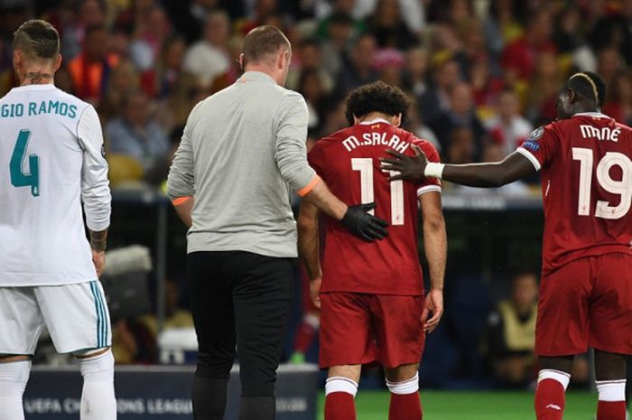 Bek Real Madrid, Sergio Ramos (kiri), melihat pemain Liverpool FC, Mohamed Salah, keluar meninggalkan lapangan dalam laga final Liga Champions di Stadion NSC Olimpiyskiy, Kiev, Ukraina pada 26 Mei 2018.