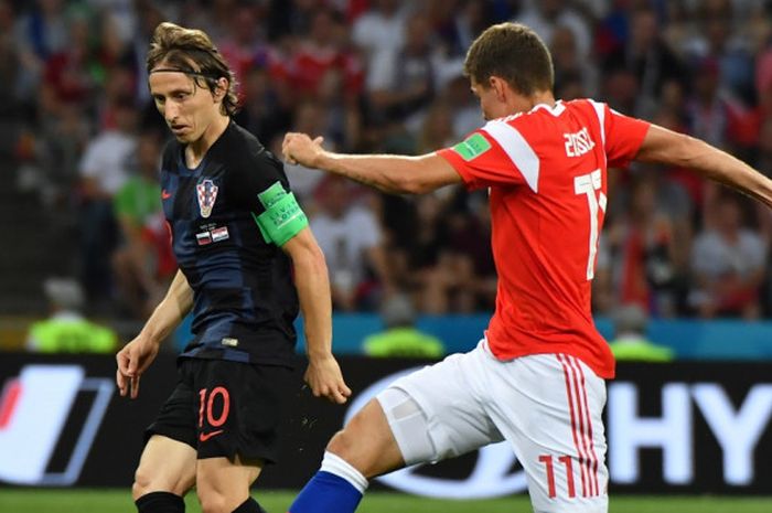 Gelandang Kroasia, Luka Modric (kiri), berduel dengan pemain Rusia, Roman Zobnin, dalam laga perempat final Piala Dunia 2018, 7 Juli 2018 di Sochi.