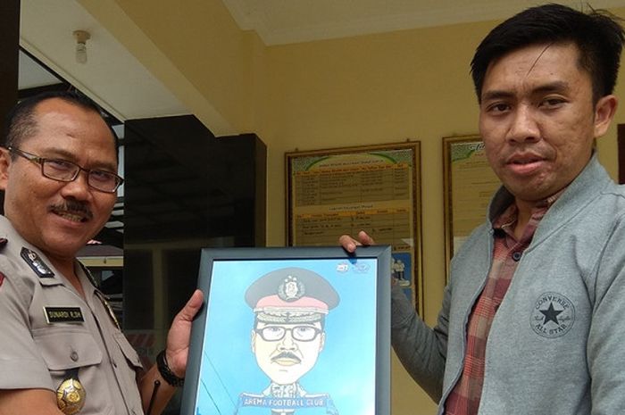 Kabag Ops Polres Malang, Kompol Sunardi Riyono mendapatkan hadiah karikatur dari perwakilan Aremania Korwil Tumpang Muhamad Rieza