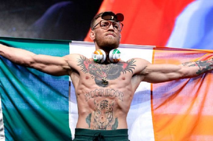 Conor McGregor hadir dengan bendera Irlandia pada acara timbang badan jelang duel versus Floyd Mayweather, Jumat (25/8/2017). 