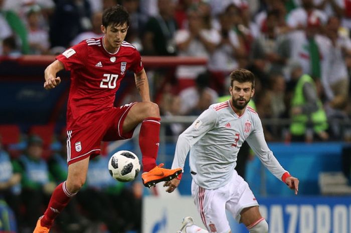 Penyerang Iran, Sardar Azmoun (kiri), mendapat pengawalan dari bek Spanyol, Gerard Pique, dalam laga Grup B Piala Dunia 2018 di Kazan Arena, Kazan, Rusia pada 20 Juni 2018.