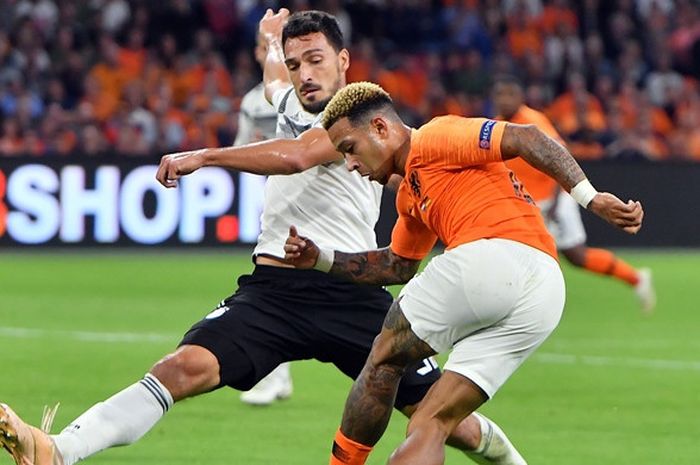 Bek Jerman, Mats Hummels (kiri), berduel dengan penyerang Belanda, Memphis Depay. Hummels menjadi salah satu calon pemain gratisan yang diincar Barcelona pada bursa transfer Januari 2024.