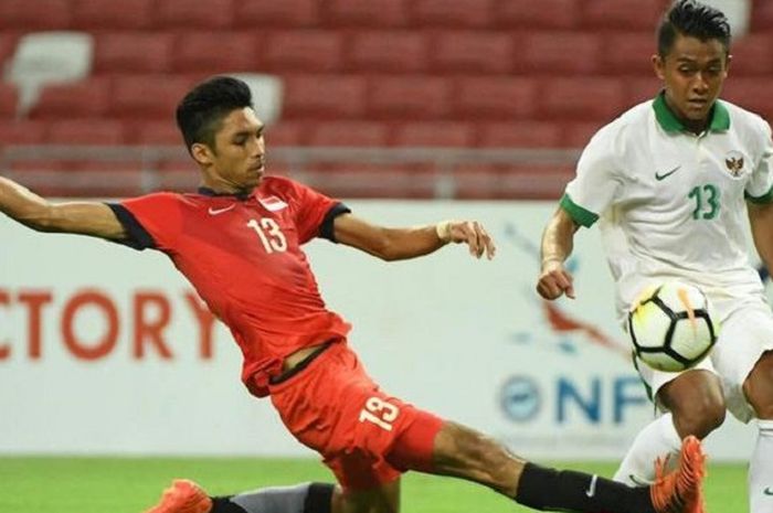 Bintang Timnas U-23 Indonesia dari Persib Bandung, Febri Hariyadi, berebut bola dengan bek Timnas U-23 Singapura Faizal Rozlan dalam uji coba internasional di Stadion Nasional, Singapura, Rabu (21/3/2018) malam WIB.