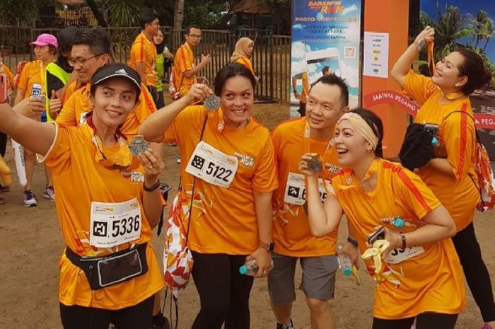 Beberapa pelari berpose di garis finish Danamon Run 2017 di Pantai Festival, Ancol, Minggu (10/9/2017).