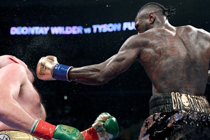 Petinju kelas berat Amerika Serikat, Deontay Wilder (kanan), melancarkan pukulan ke arah Tyson Fury (Inggris) pada pertarungan memperebutkan gelar juara WBC, di Staples Center, Los Angeles, Amerika Serikat, Sabtu (1/12/2018).