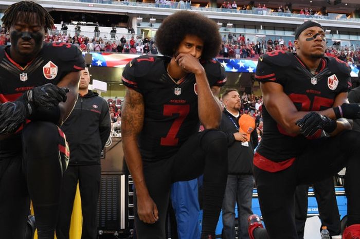 Pemain NFL dari tim San Francisco 49ers, Colin Kaepernick (tengah, #7), didampingi dua rekan setimnya Eli Harold (#58) dan Eric Reid (#35), melakukan aksi berlutut dengan satu kaki saat lagu kebangsaan Amerika Serikat (AS), Star Spangled Banner, dinyanyikan sebelum laga melawan Arizona Cardinals di Levi's Stadium, Santa Clara, California, 6 Oktober 2016. Aksi ini sebagai bentuk protes anti-rasial.