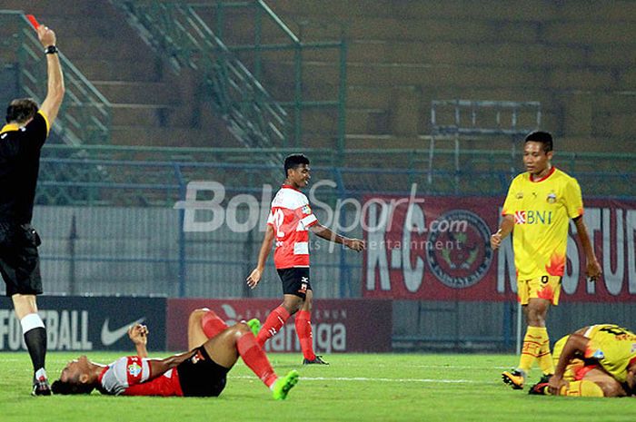 Wasit asal Iran, Seyed Vahird Kazemi (kiri), memberikan kartu merah kepada pemain Madura United, Rizky Dwi Febrianto (kedua dari kiri), akibat menekel dengan keras pemain Bhayangkara FC, TM Ichsan, dalam laga pekan ke-33  Liga 1 yang berakhir dengan skor 1-3 di Stadion Gelora Bangkalan, Jawa Timur, (08/11/2017).