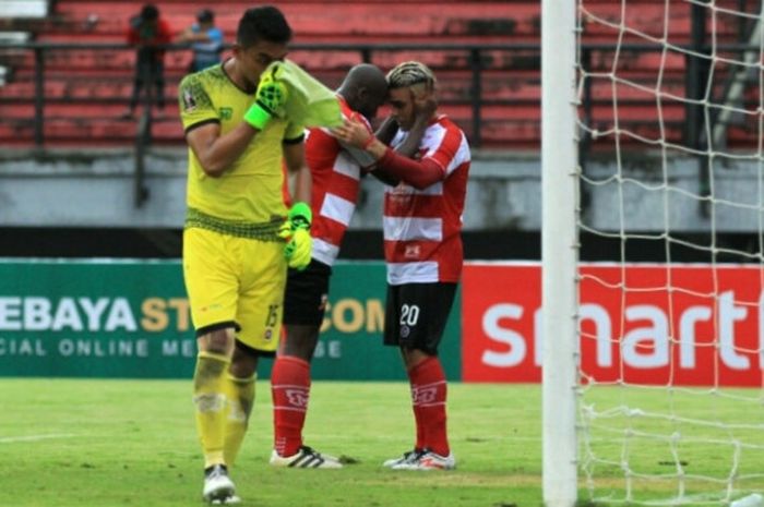 Kiper PS TNI, Tegu Amiruddin (depan) mengusap keringat pada wajahnya seusai gawangnya kebobolan oleh pemain depan Madura United, Cristian Gonzales (kanan) untuk laga lanjutan Grup C Piala Presiden 2018 di Gelora Bung Tomo, Kota Surabaya, Selasa (23/1/2018).