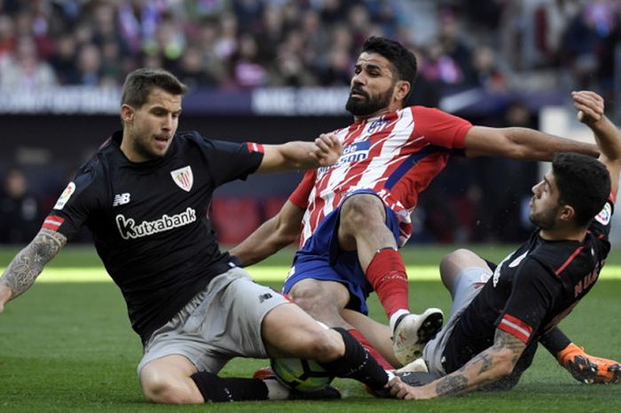 Aksi striker Atletico Madrid, Diego Costa (tengah), saat berduel dengan dua bek Athletic Bilbao, Inigo Martinez (kiri) dan Unai Nunez, dalam pertandingan La Liga Spanyol 2017-2018 di Stadion Wanda Metropolitano, Madrid, Spanyol, pada Minggu, 18 Februari 2018.