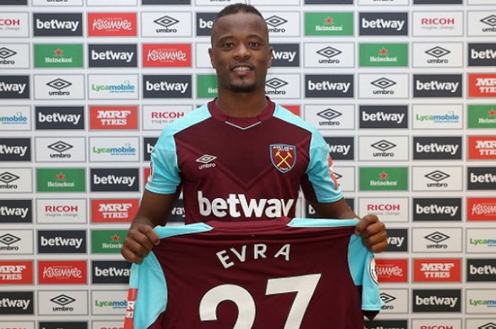 Bek baru West Ham United, Patrice Evra, berpose bersama seragam tim setelah resmi bergabung pada Rabu (7/2/2018).