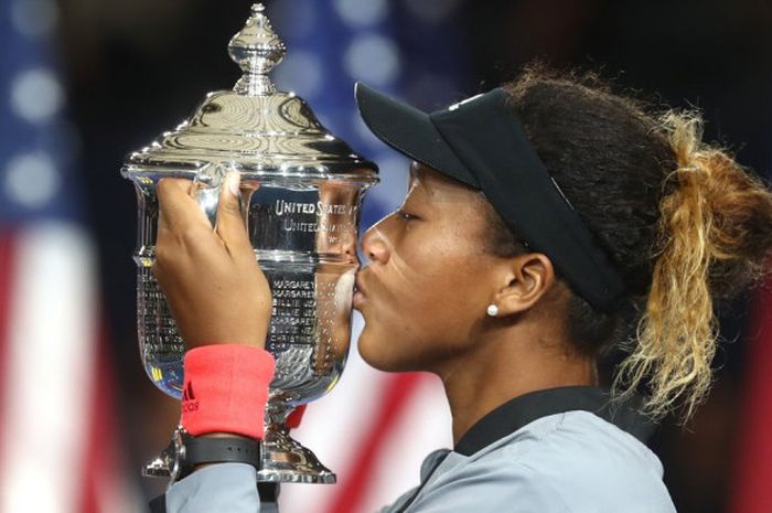 Petenis Jepang, Naomi Osaka, mencium trofi Grand Slam pertamanya usai menang 6-2, 6-4 atas Serena Williams (Amerika Serikat) di final US Open 2018 pada Minggu (9/9/2018).