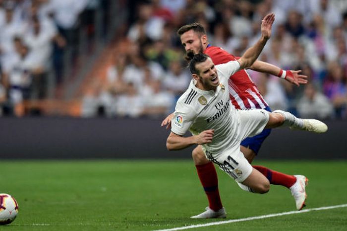 Pemain Real Madrid, Gareth Bale, terjatuh saat berduel dengan pilar Atletico Madrid, Saul Niguez, dalam pertemuan kedua tim pada laga pekan ke-7 Liga Spanyol di Santiago Bernabeu, Sabtu (29/9/2018) waktu setempat atau Minggu dini hari WIB. 