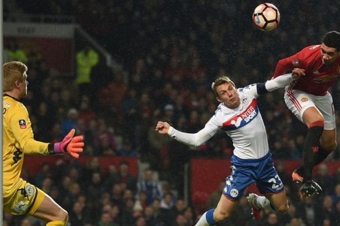 Bek Manchester United, Chris Smalling (kanan), menyundul bola dalam laga ronde keempat Piala FA kontra Wigan Athletic di Stadion Old Trafford, Manchester, Inggris, 29 Januari 2017.