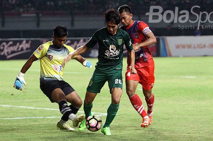 Kiper Persigo Semeru FC, M. Purjiantoro (kiri) mencoba menghalau bola dari kaki penyerang Persebaya, Rishadi Fauzi pada laga di Gelora Bung Tomo, Sabtu (30/9/2017).