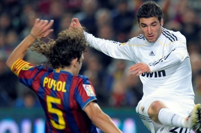 Gonzalo Higuain (kanan) melepaskan tembakan yang berusaha diblok oleh Carles Puyol dalam partai La Liga antara FC Barcelona versus Real Madrid di Camp Nou, Barcelona, 29 November 2009.