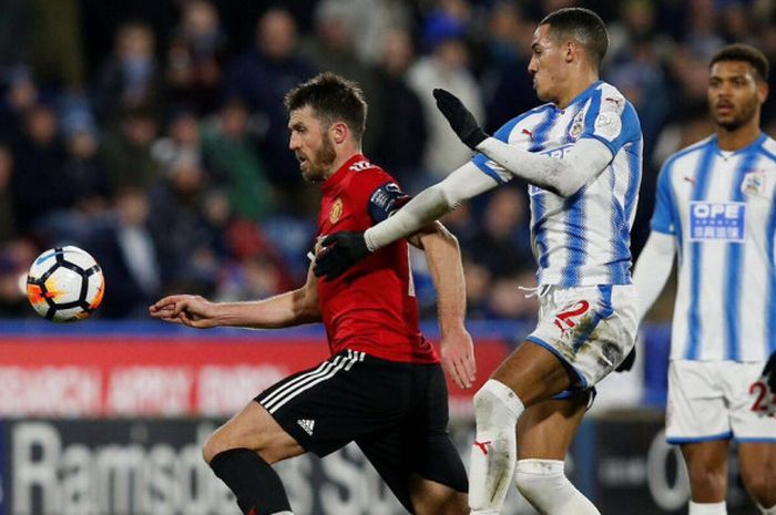 Gelandang gaek Manchester United, Michael Carrick, berusaha lolos dari hadangan pemain Huddersfield Town, Tom Ince, saat keduanya bertemu di Piala FA pada 18 Februari 2018.