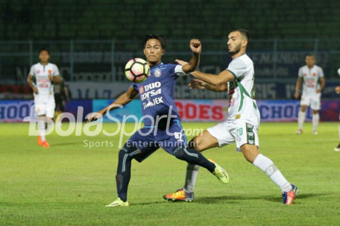 Pemain Arema FC Johan Alfarizie (tengah) berusaha mempertahankan bola dari hadangan gelandang PS TNI