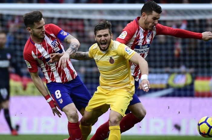 Gelandang Girona, Cristian Portugues Manzarena alias Portu(tengah), saat berduel dengan dua pemain Atletico Madrid, Saul Niguez (kiri) dan Lucas Hernandez, dalam pertandingan La Liga Spanyol 2017-2018 di Stadion Wanda Metropolitano, Madrid, Spanyol, pada Sabtu (20/1/2018).