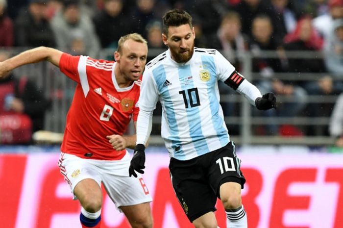 Kapten Argentina, Lionel Messi (kanan), berduel dengan gelandang Rusia, Denis Glushakov, dalam laga persahabatan di Stadion Luzhniki, Moscow, Rusia, pada 11 November 2017.