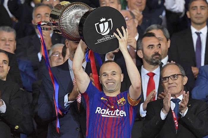      Kapten Barcelona, Andres Iniesta, mengangkat trofi juara Copa del Rey 2018 yang diraihnya pasca mengalahkan Sevilla 5-0 di Stadion Wanda Metropolitano, Madrid, pada Minggu (22/4/2018).     