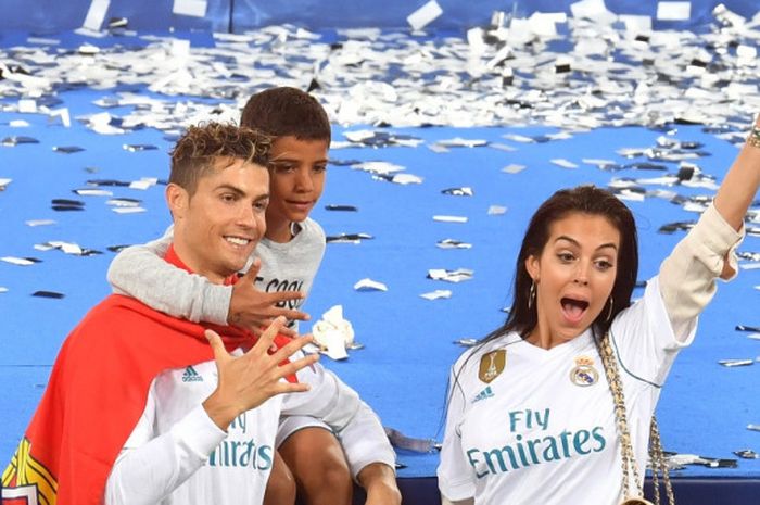 Cristiano Ronaldo berpose bersama anaknya, Cristiano Ronaldo Junior, dan pasangannya, Georgina Rodriguez, seusai Real Madrid menjuarai Liga Champions di Stadion Olimpiyskiy, Kiev, Ukraina pada 26 Mei 2018.