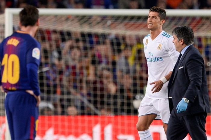   Megabintang FC Barcelona, Lionel Messi (kiri), menyaksikan megabintang Real Madrid, Cristiano Ronaldo, berjalan kesakitan dalam laga Liga Spanyol di Stadion Camp Nou, Barcelona pada 6 Mei 2018.  