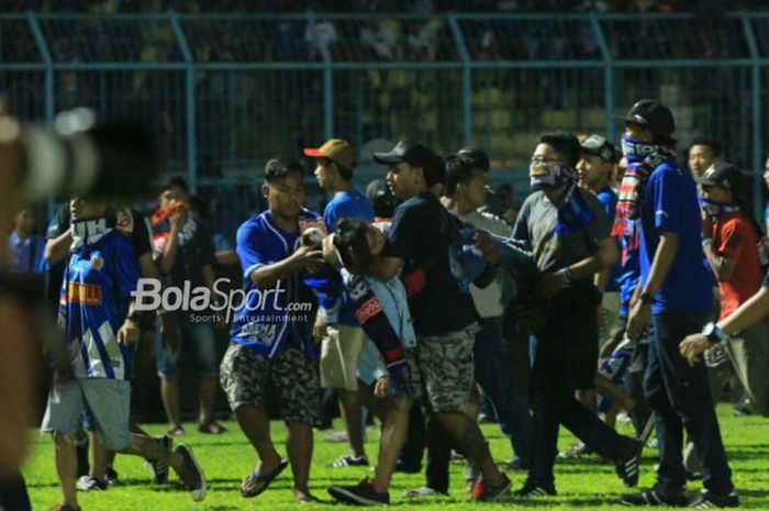     Seorang penonton dievakuasi oleh para suporter di  lapangan Stadion Kanjuruhan seusai pertandingan Liga 1 2018, Arema FC Vs Persib Bandung, Minggu (15/4/2018)