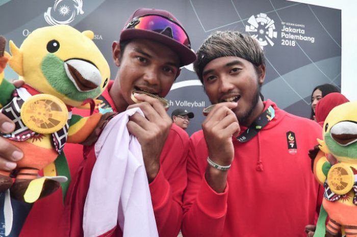 Pebola voli pantai putra Indonesia Gilang Ramadhan (kanan) dan Danangsyah Yudistira Pribadi (kiri) menggigit medali perunggunya seusai mengalahkan wakil China pada pertandingan perebutan medali perunggu voli pantai putra Asian Games 2018 di arena Jakabaring Sport City, Palembang, Sumsel, Selasa (28/8/2018).