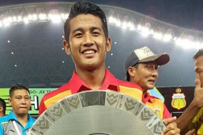 Putu Gede memegang piala Juara Liga 1