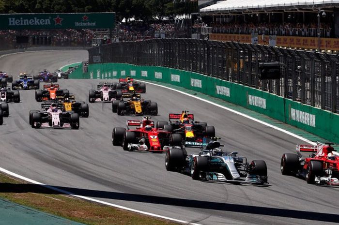 Sebastian Vettel (merah) merebut posisi terdepan dari Valtteri Bottas (abu-abu) selepas start balapan F1 GP Brasil yang berlangsung di Sirkuit Jose Carlos Pace, Sao Paulo, Brazil (12/11/2017).