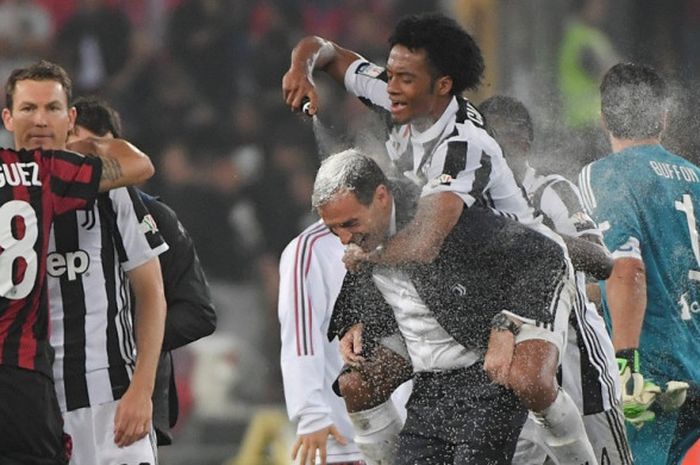 Pemain Juventus, Juan Cuadrado (atas), menyemprotkan krim ke atas kepala sang pelatih, Massimiliano Allegri, seusai mengalahkan AC Milan dalam laga final Coppa Italia di  Stadion Olimpico, Roma pada 9 Mei 2018.