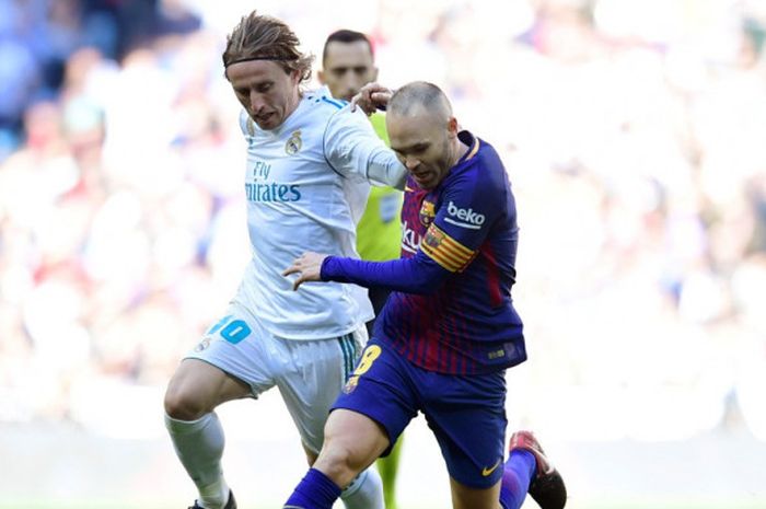 Gelandang FC Barcelona, Andres Iniesta (kanan), berduel dengan pemain Real Madrid, Luka Modric, dalam laga Liga Spanyol di Stadion Santiago Bernabeu, Madrid, pada 23 Desember 2017.