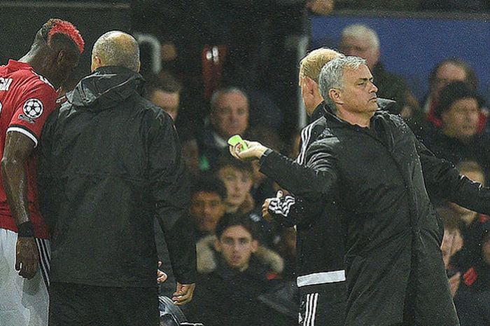 Manajer Manchester United, Jose Mourinho (kanan), melempar ban kapten yang sebelumnya dipakai Paul Pogba (kiri), kepada Ashley Young dalam laga  melawan Basel pada ajang Liga Champions 2017-2018 Grup A di Stadion Old Trafford, Manchester, Inggris, ada 12 September 2017. Pogba Ditarik keluar akibat cedera.