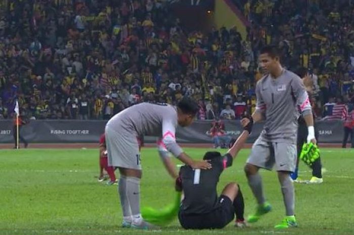 Kiper Malaysia membantu Satria Tama untuk berdiri dan memberi semangat.