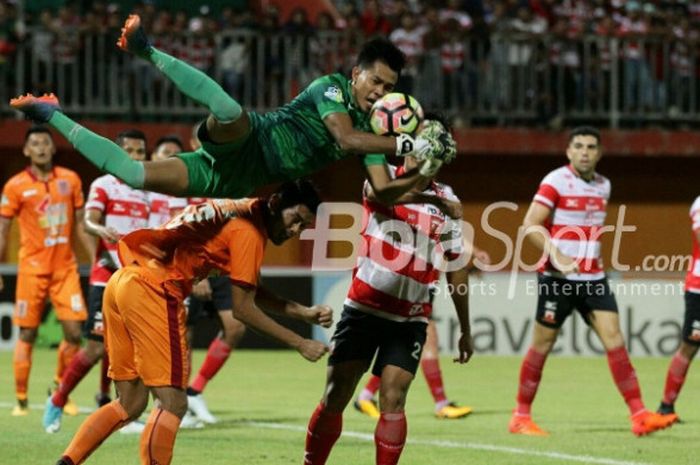 Kiper Madura United, Angga Saputra, menangkap bola saat tampil pada pertandingan Liga 1 melawan Borneo FC, Jumat (13/10/2017). 