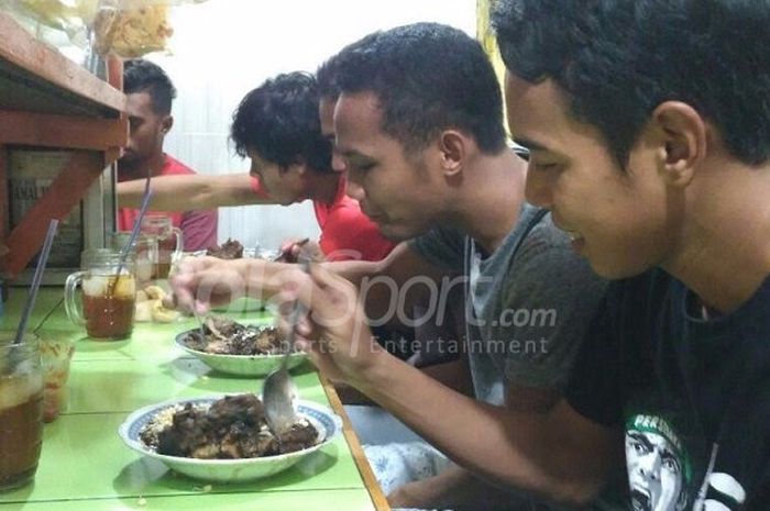 Gelandang Persebaya, Misbahkus Solikin (kanan) dan Oktavianus Fernando serta beberapa pemain lainnya menyantap kuliner rawon usai latihan.