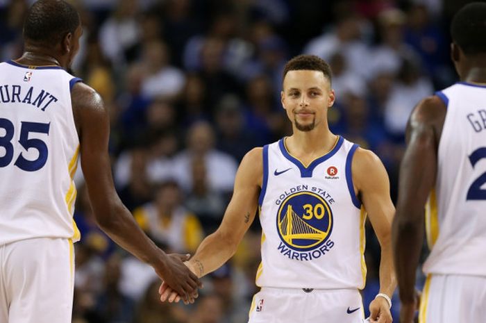 Pebasket Golden State Warriors, Stephen Curry (tengah), melakukan selebrasi dengan kedua rekan setimnya, Kevin Durant (#35) dan Draymond Green (#23), saat tengah menjalani laga pembuka NBA musim 2017-2018 melawan Houston Rockets di Oracle Arena, Selasa (17/10/2017) malam waktu setempat.